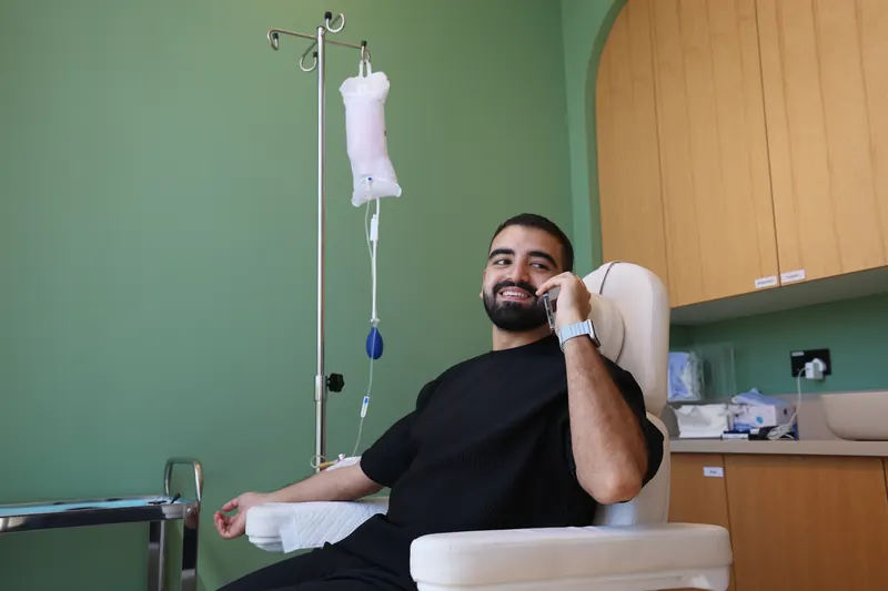 عميل يبتسم خلال مكالمة هاتفية أثناء تلقي محلول وريدي