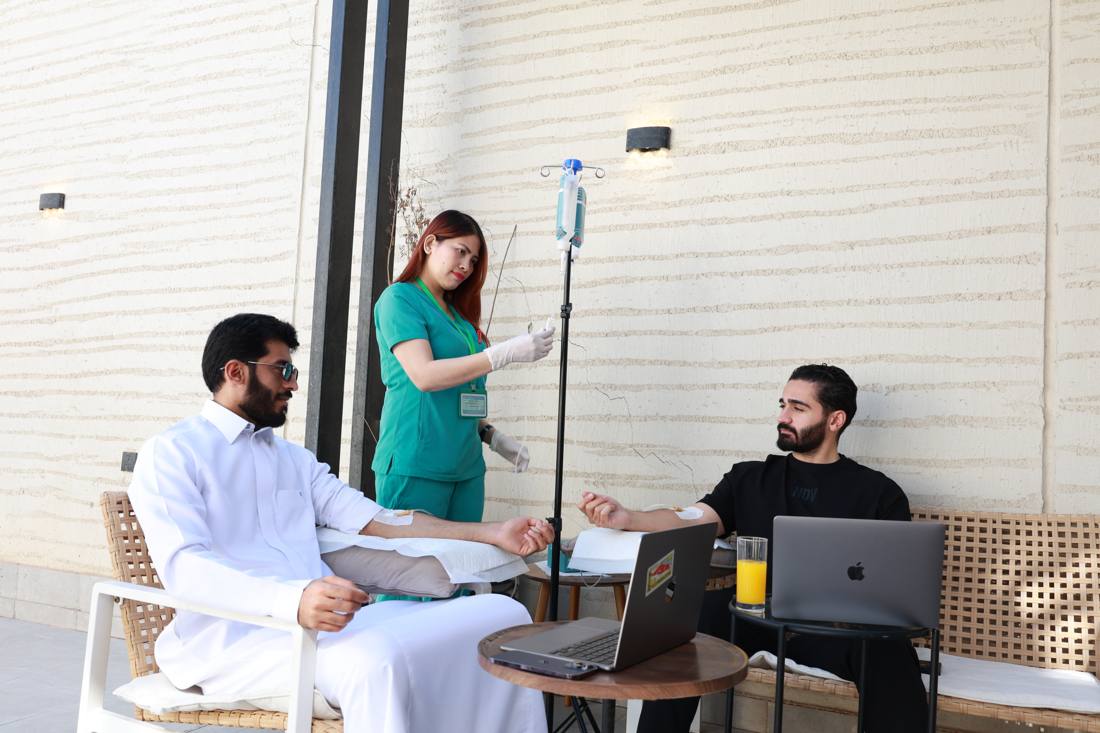 A nurse administering an IV drip to two clients in a relaxed outdoor setting