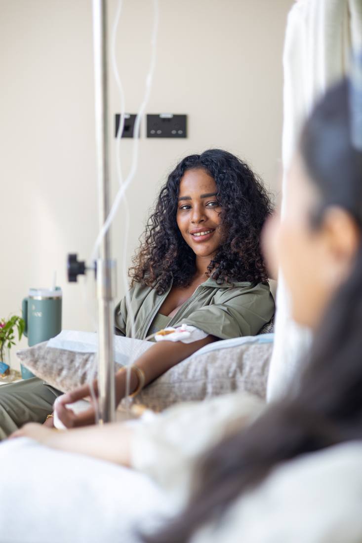 A patient smiling while her Myers Cocktail IV drip runs