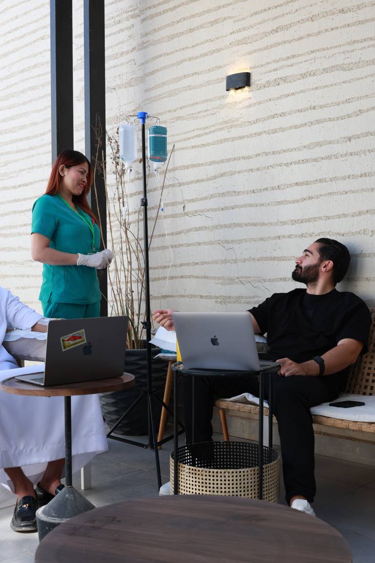 A nurse checking on patients during their IV drips on the clinic terrace